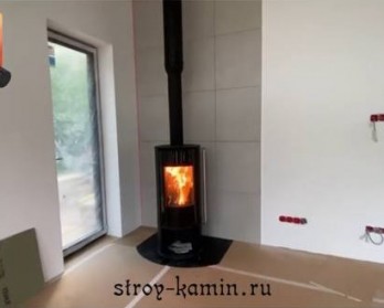 Дровяная печь Астов R1.0 с дымоходом Феникс, в углу гостиной загородного дома - современная и греет
